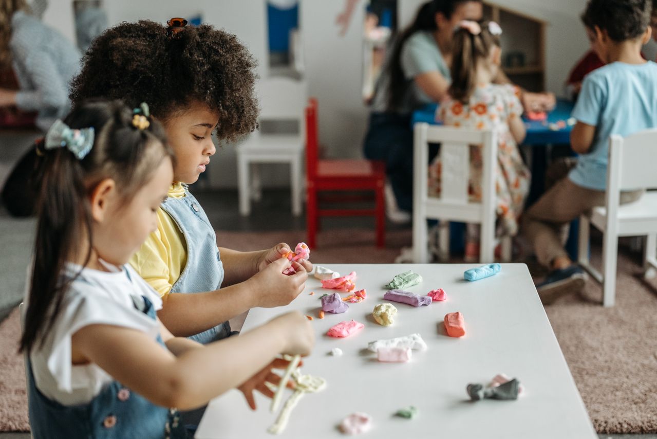 Children at a preschool table playing with colorful modeling clay